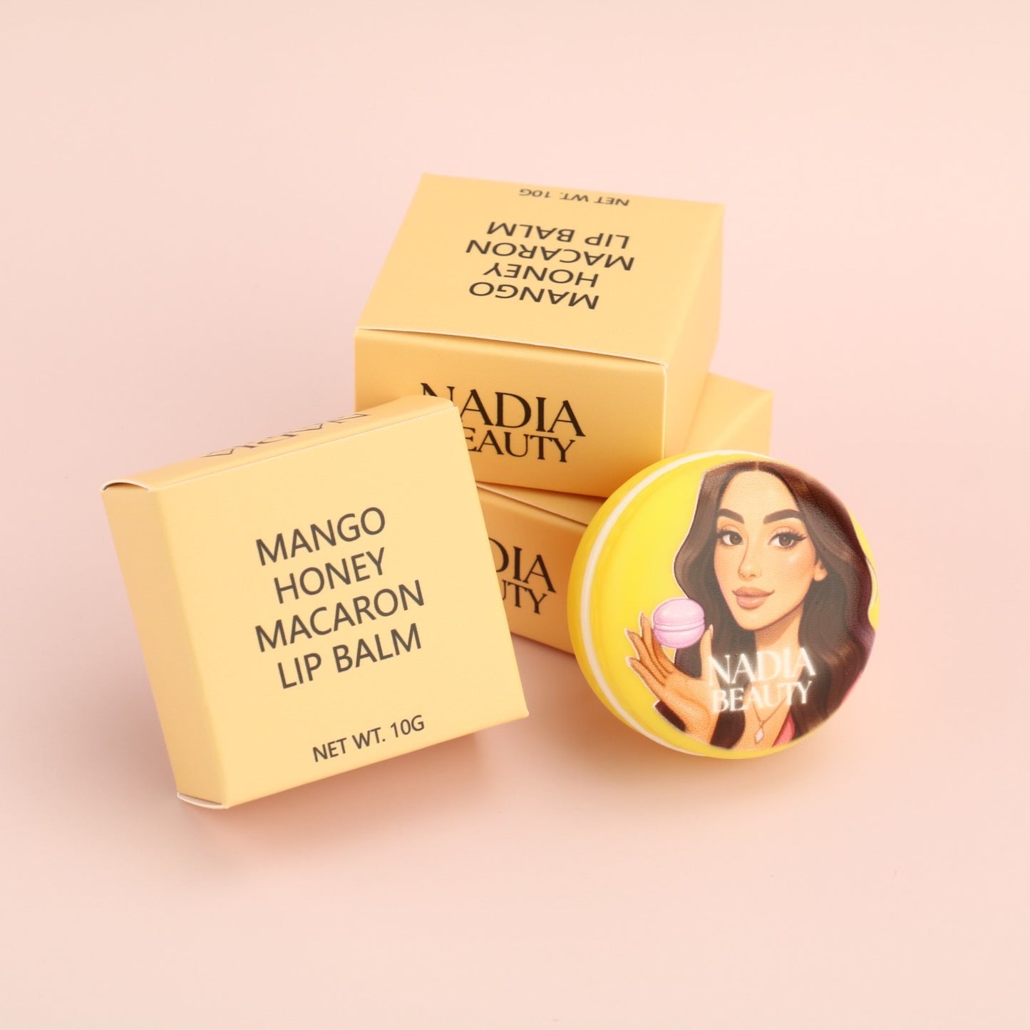Nadia Beauty Mango Honey Macaron Lip Balm packaging on a pink background